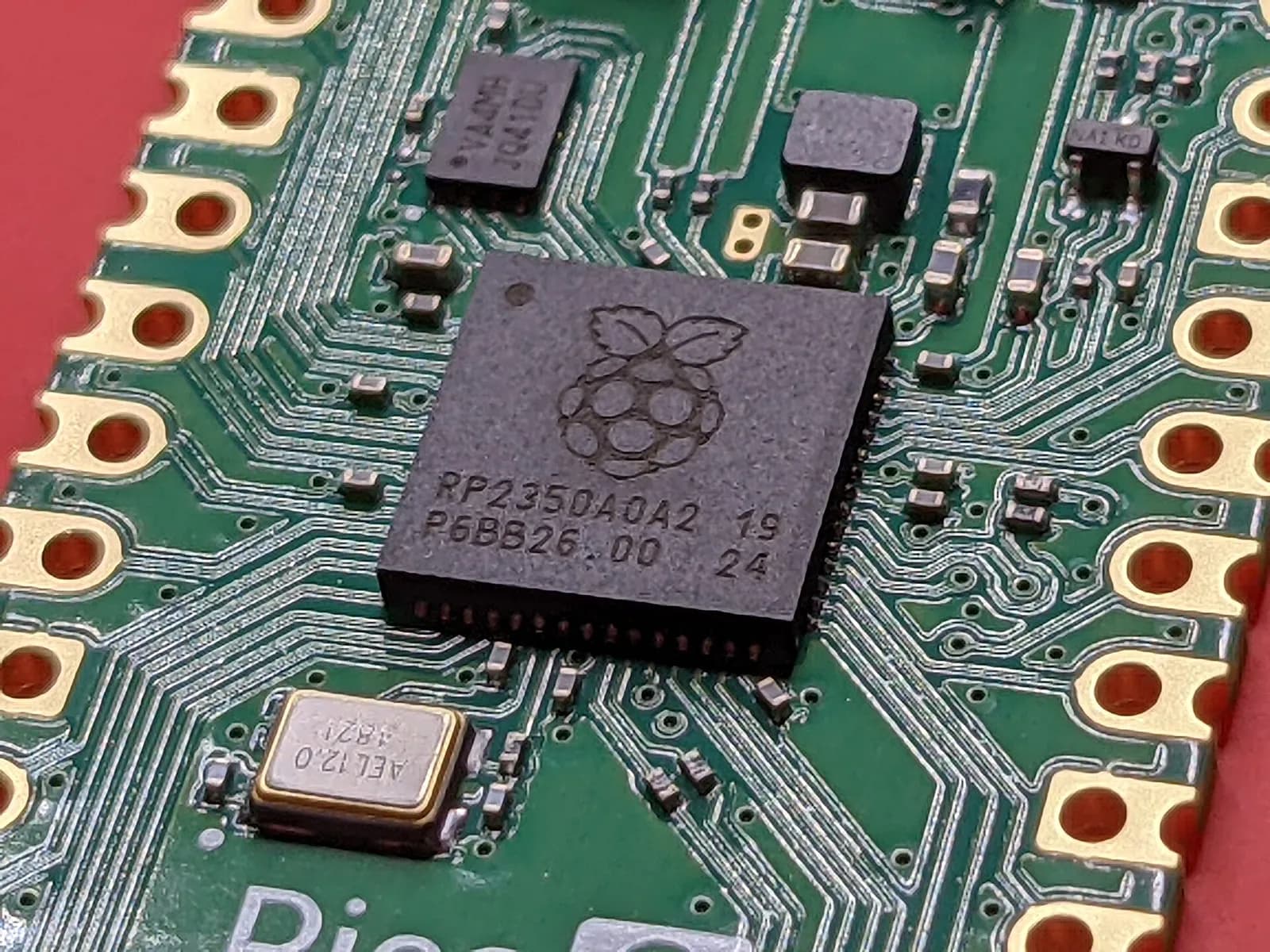 A microcontroller and the small parts around it on a green circuit board, close up